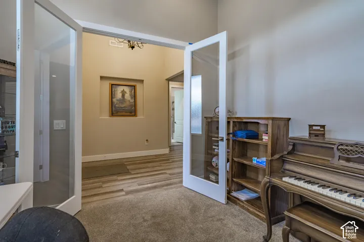 Glass-paneled double doors open to a spacious room with carpet flooring
