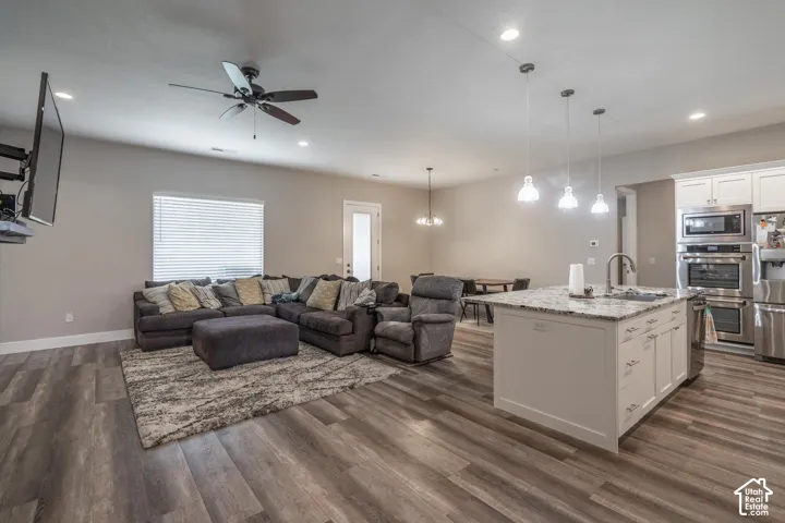 Open-concept common area featuring wood-finish flooring, recessed lighting, a ceiling fan, and white kitchen cabinetry with stainless steel appliances