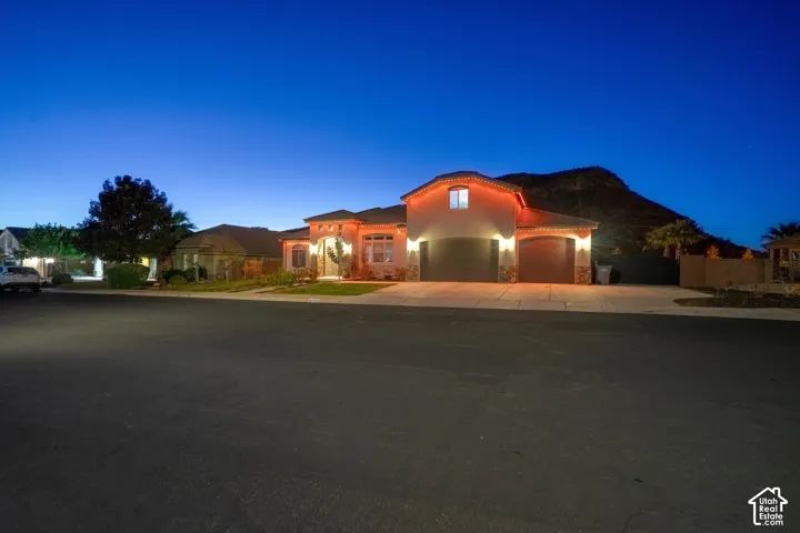 Stucco exterior with stone accents, arched entry, two-car garage, and desert landscaping