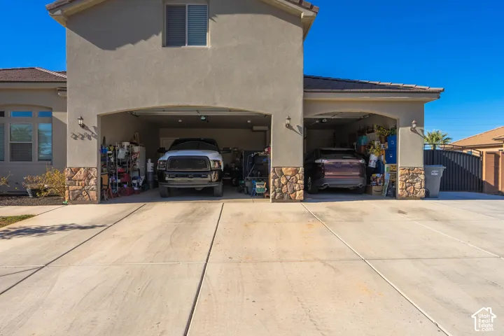 Stucco exterior with stone accents, two-car garage bays, concrete driveway, and upper-level window