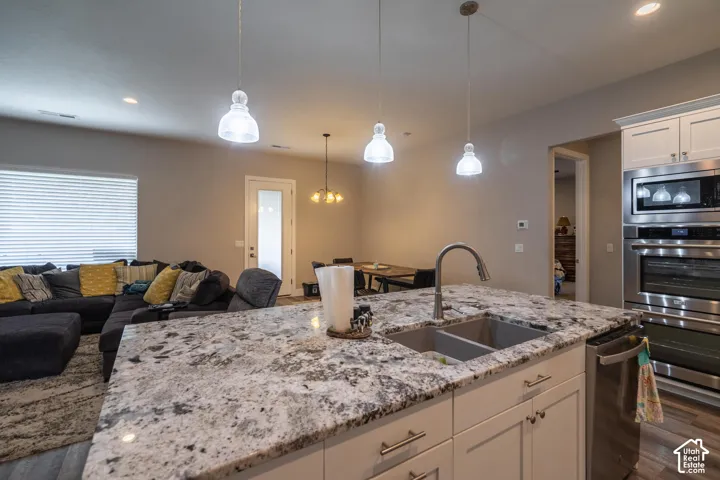 Kitchen island with a double basin sink, gooseneck faucet, and pendant lighting