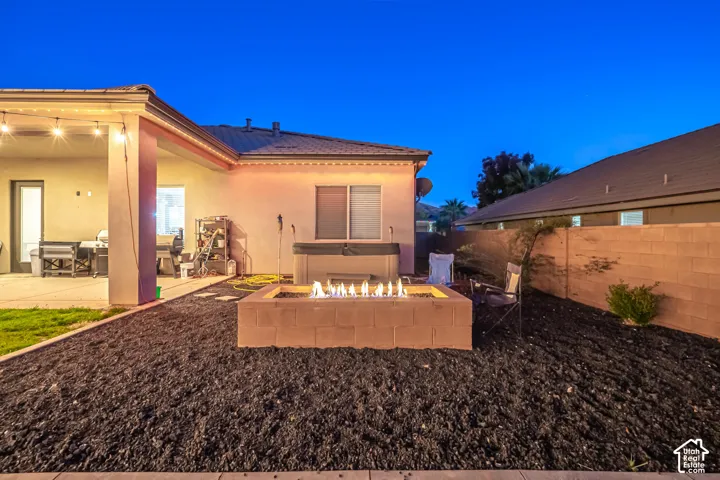 Outdoor living area featuring a covered patio, built-in fire pit, and a hot tub