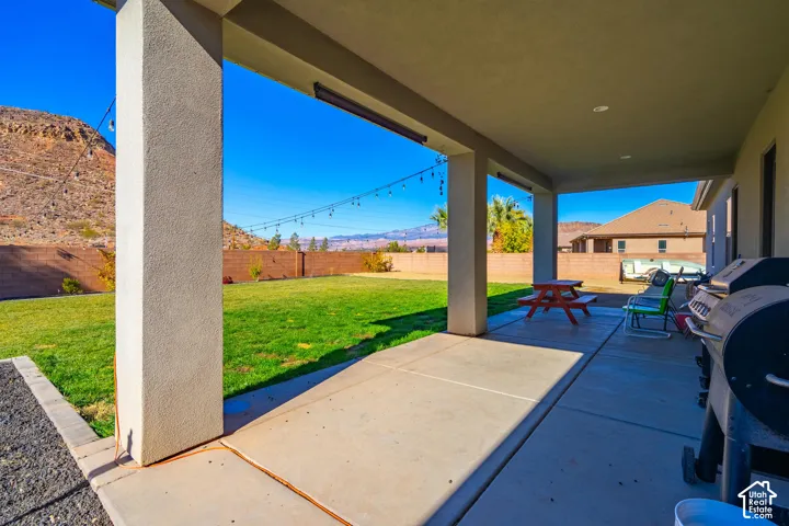 Covered patio with concrete flooring, stucco pillars, and a spacious green lawn