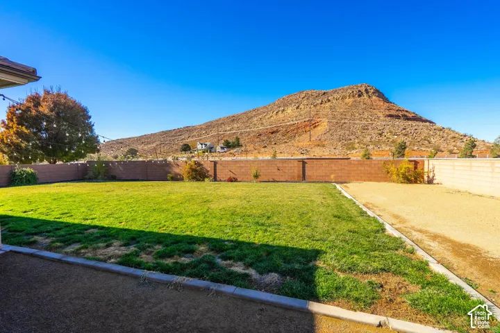 Expansive backyard featuring a manicured lawn, a large unlandscaped area, and a solid brick perimeter fence