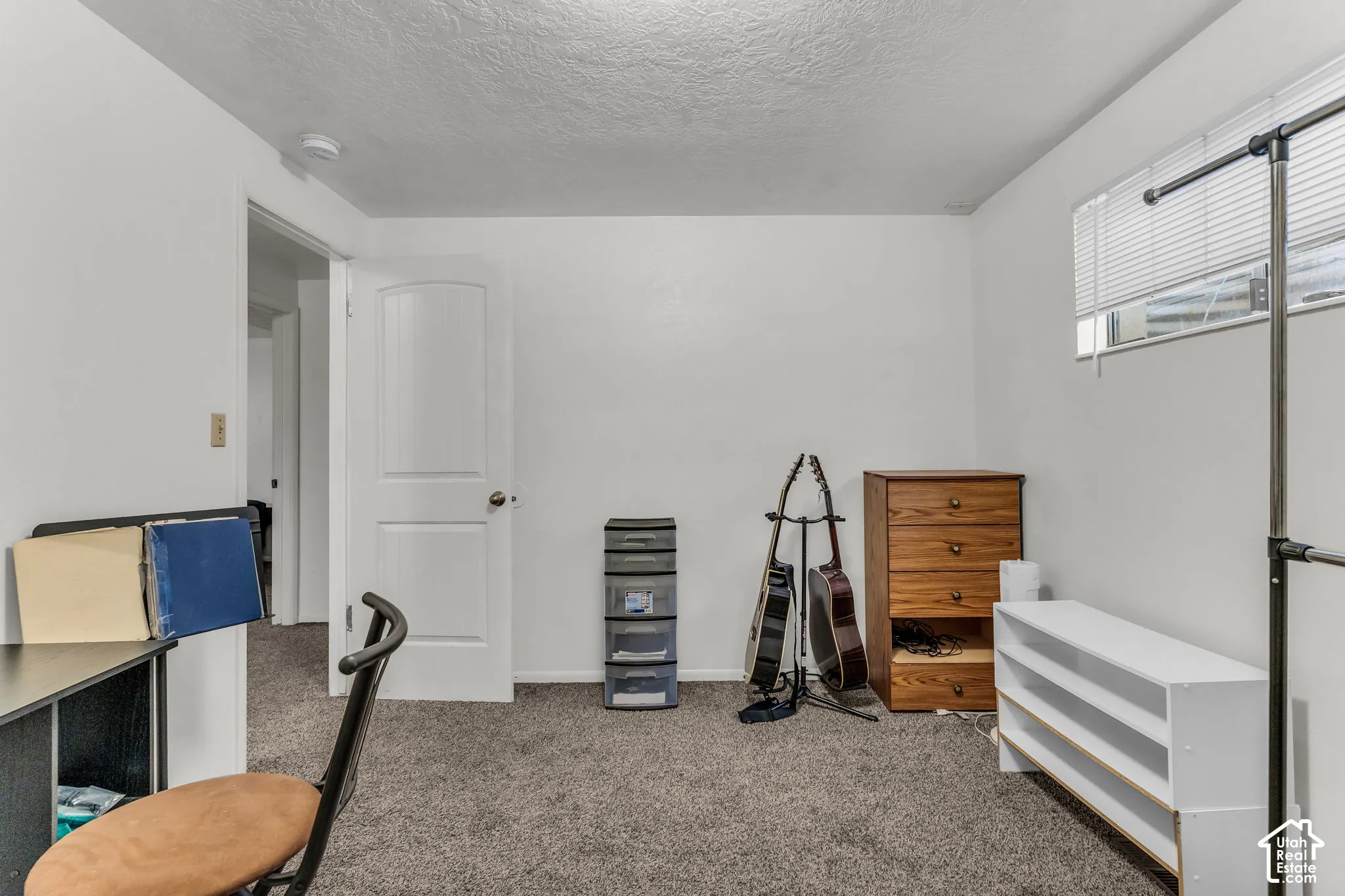 Carpeted flooring, white painted walls, and a window with blinds