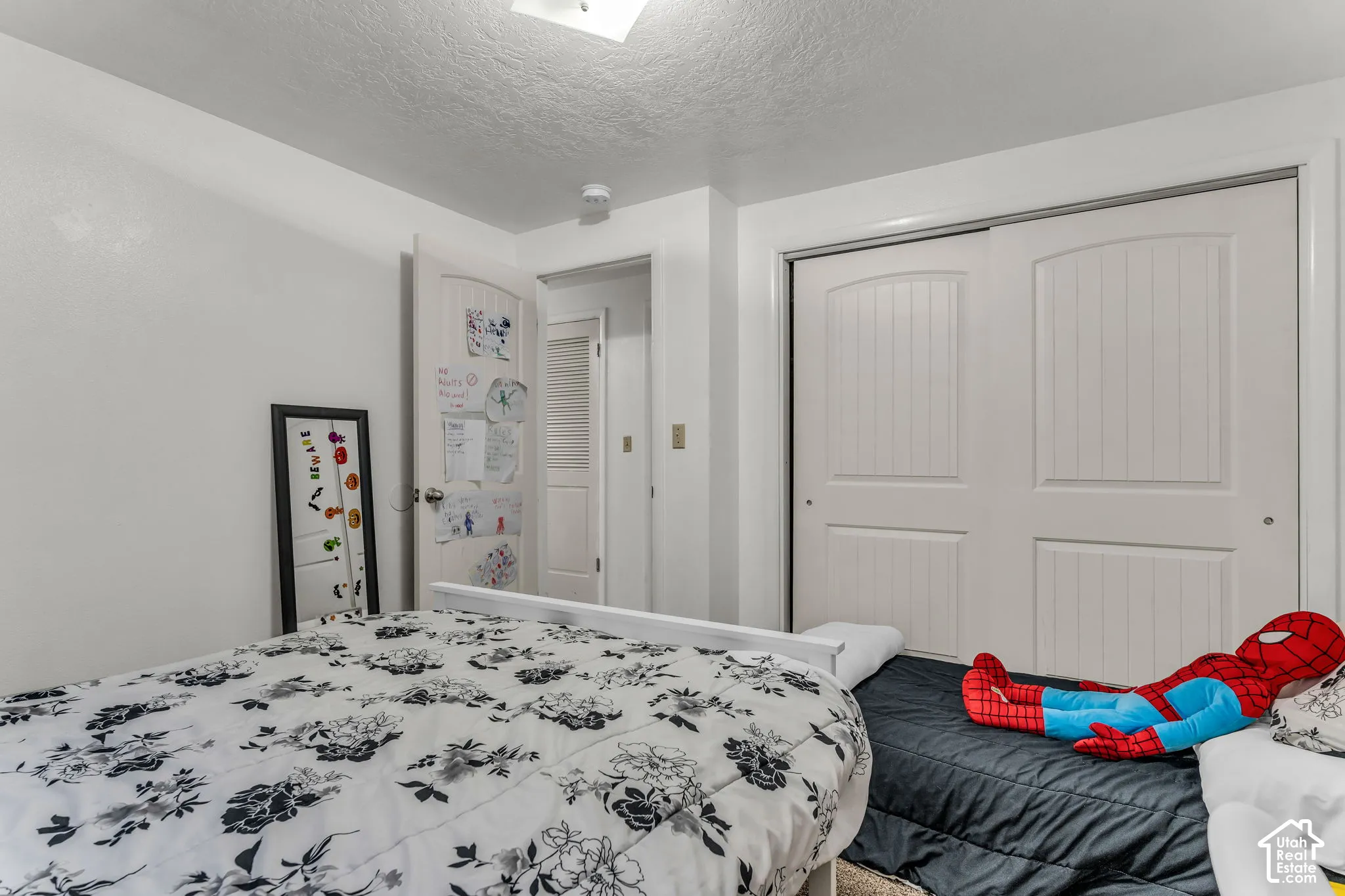 White painted walls, textured ceiling, white sliding closet doors, and a white interior door