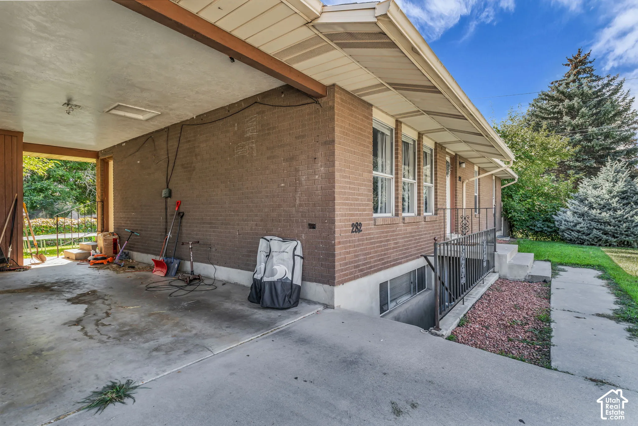 Brick exterior with an attached carport, featuring a concrete driveway and walkway