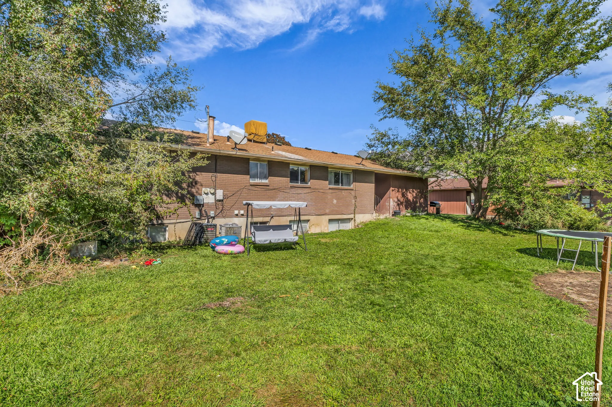 Expansive grassy yard with mature trees and a brick exterior