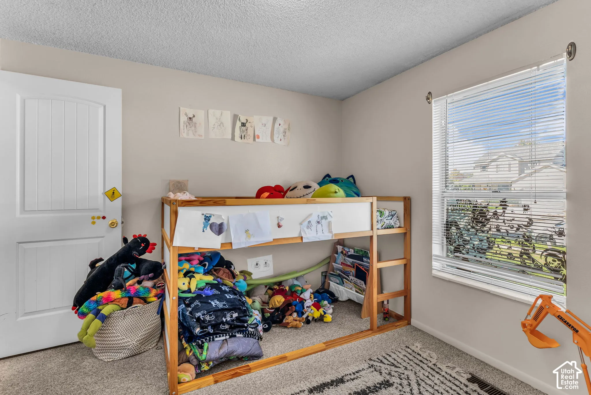 Neutral wall paint, textured ceiling, window with blinds, white interior door with paneling, and carpet flooring