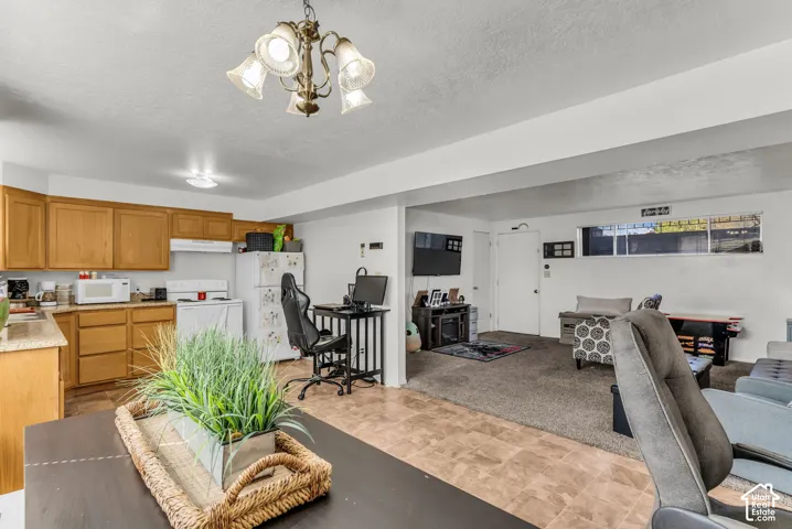 Kitchen with light wood cabinetry, white appliances, and a vinyl floor