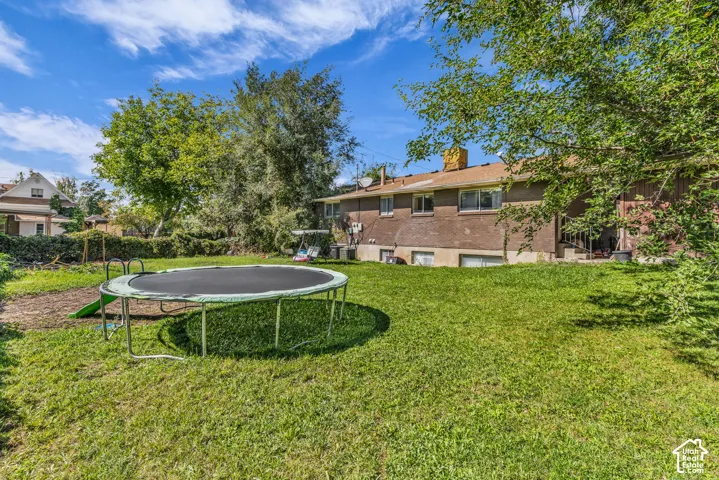 Spacious backyard featuring a sloped lawn and mature perimeter trees