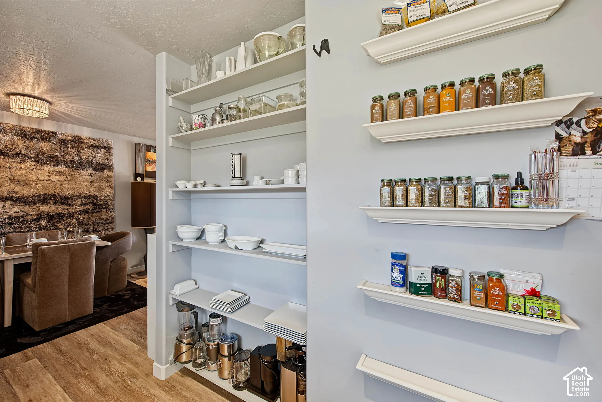 Built-in shelving for organized storage, wood-finish flooring, and a modern chandelier illuminating the dining area