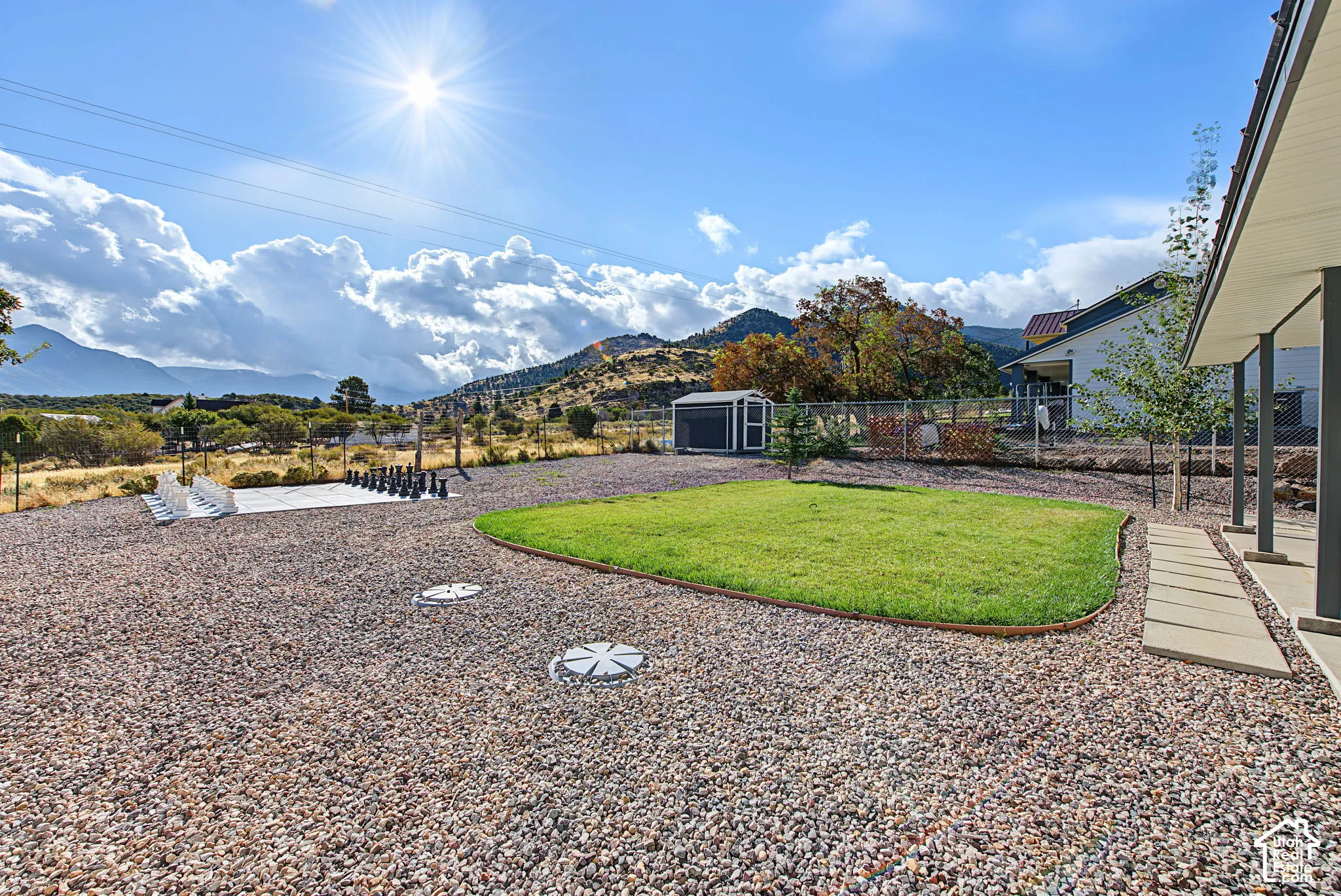 Expansive outdoor area featuring a gravel ground cover, a manicured lawn area, and a detached shed