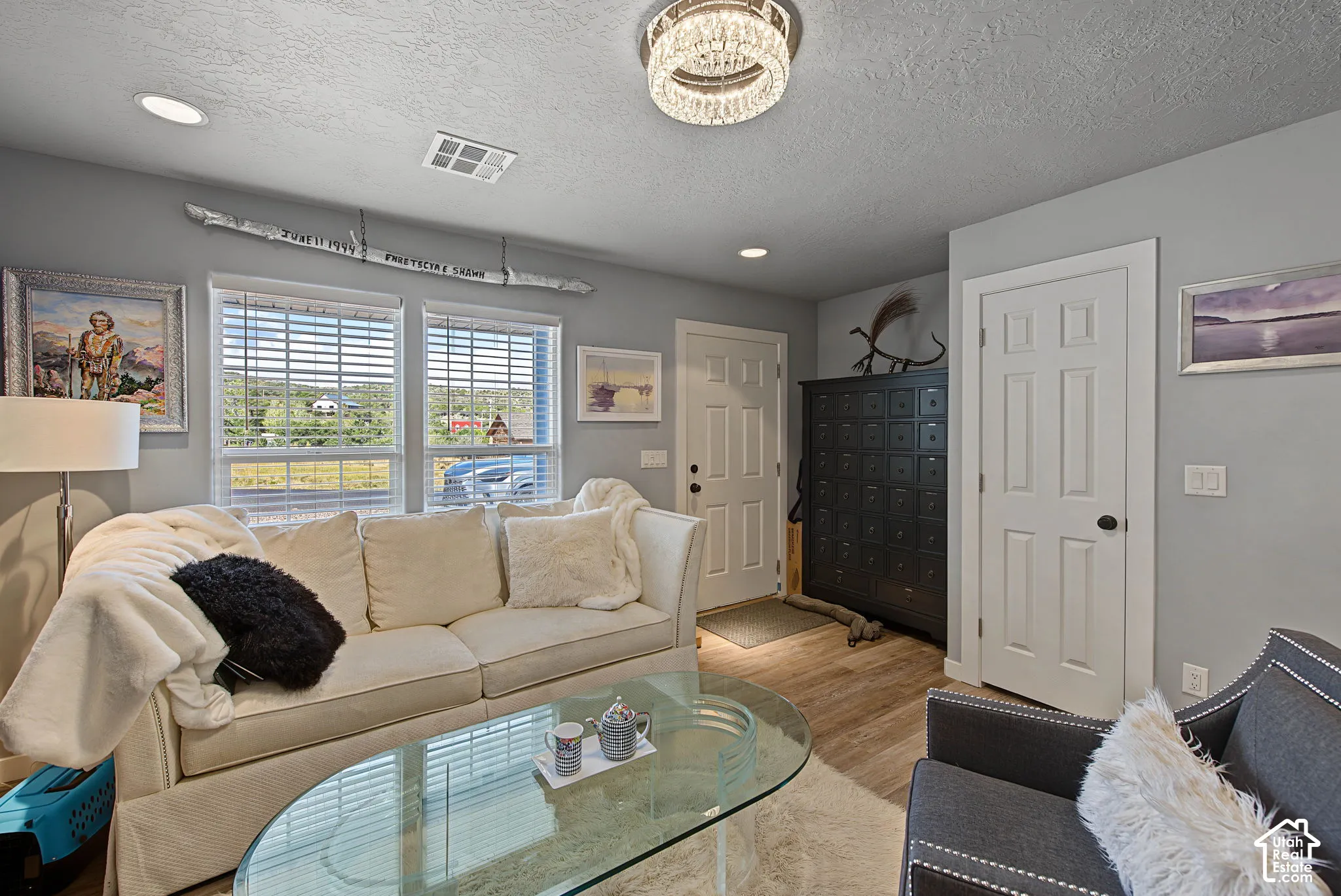 Recessed lighting, wood-finish flooring, and a crystal-adorned chandelier