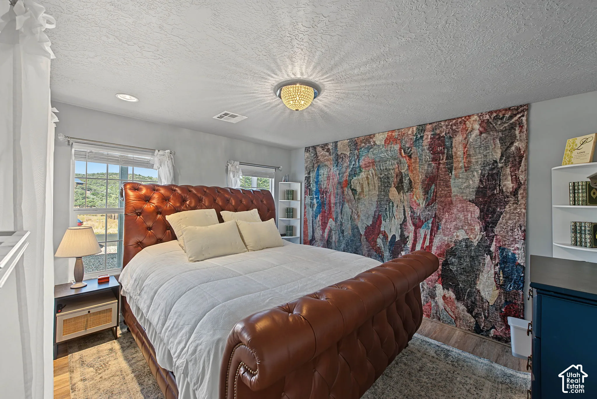 Recessed lighting with a central chandelier, multiple windows, built-in shelving, and wood-finish flooring