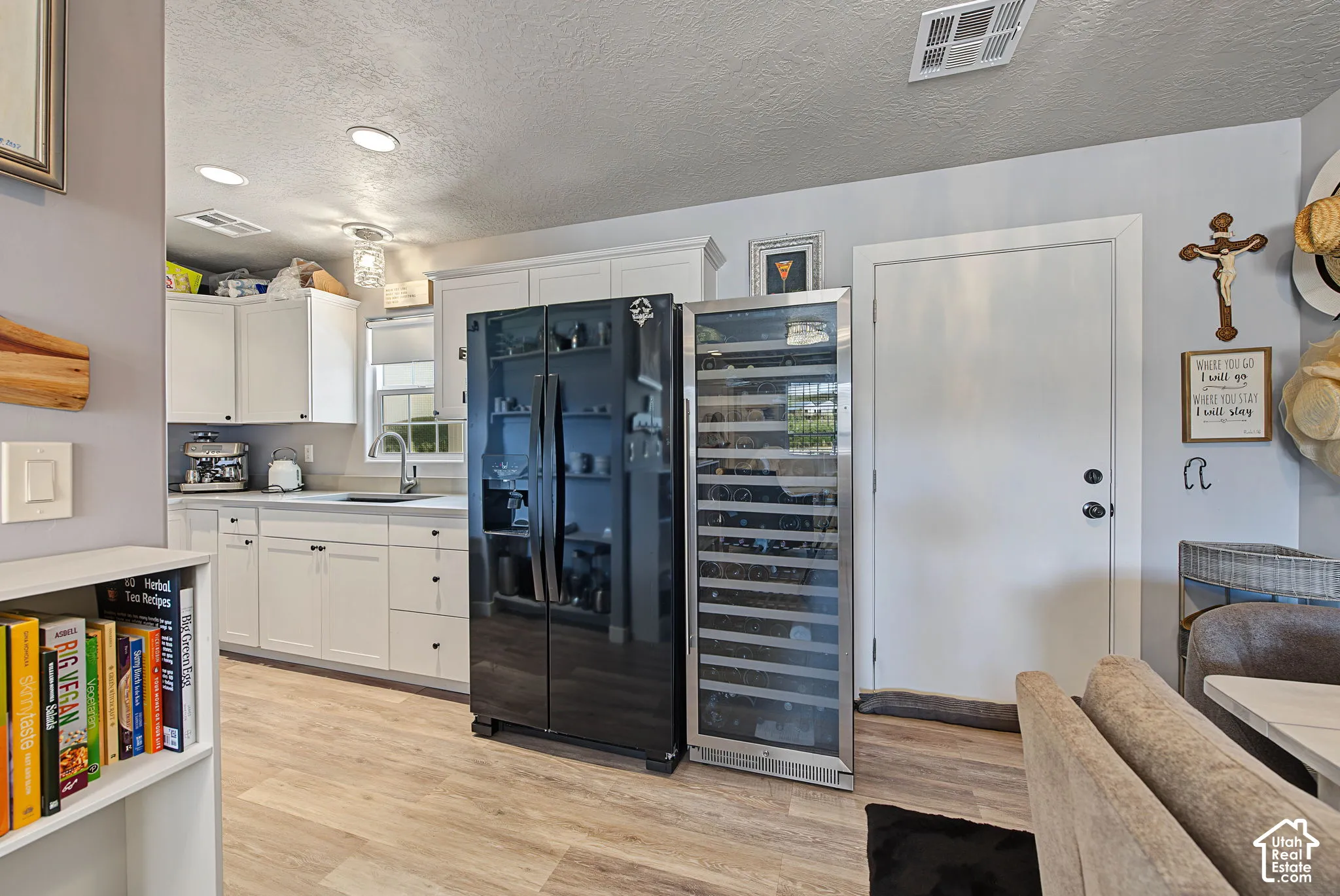 Kitchen featuring white cabinetry, wood-finish flooring, a stainless steel sink, and a built-in wine refrigerator