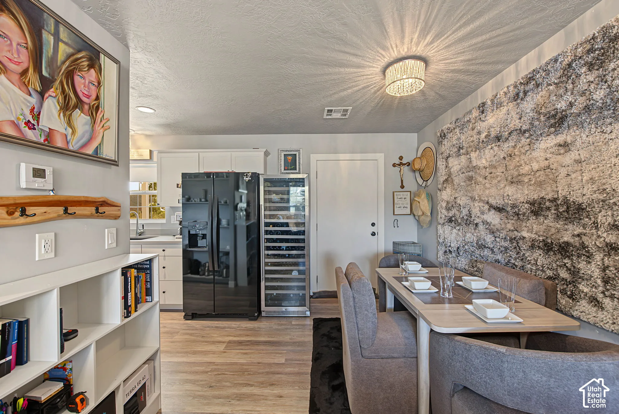 Wood-finish flooring, built-in shelving, white cabinetry, dark-finish refrigerator, and a built-in wine cooler