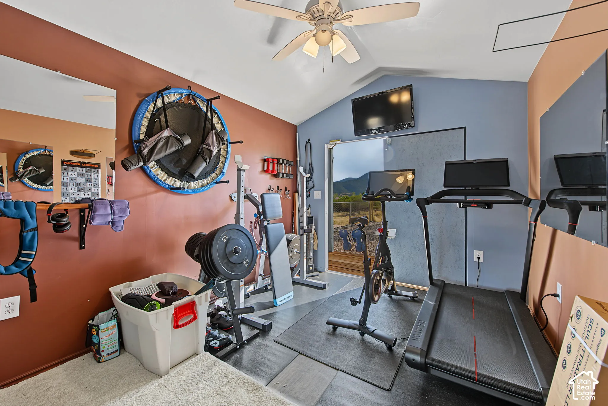 Vaulted ceiling with a ceiling fan, wall-mounted television, and direct outdoor access