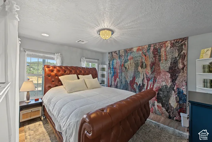Recessed lighting with a central chandelier, multiple windows, built-in shelving, and wood-finish flooring