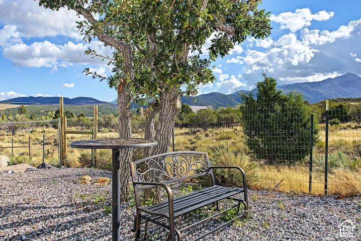 Gravel patio area featuring a mature tree, perimeter fencing, and distant mountains