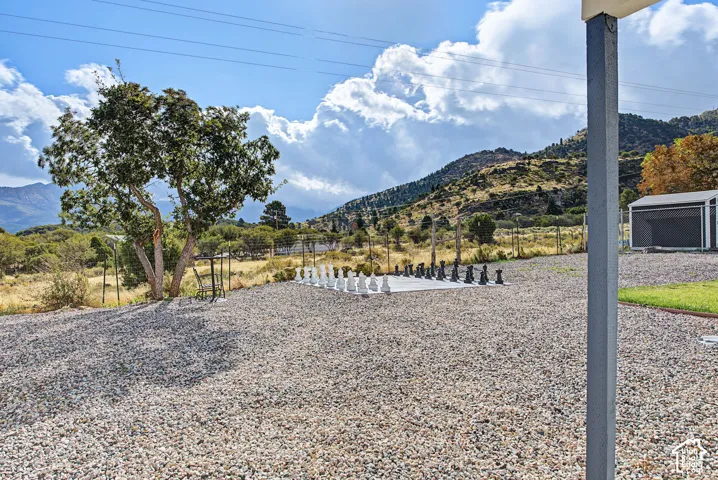 Gravel ground cover with an outdoor chess set and mature tree, set against a mountain backdrop