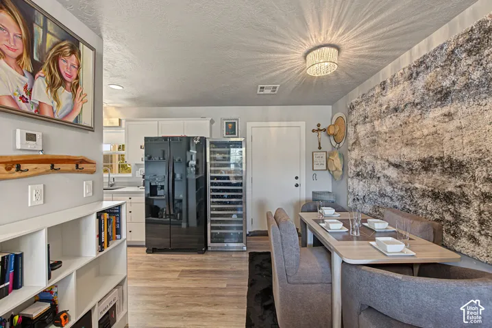 Wood-finish flooring, built-in shelving, white cabinetry, dark-finish refrigerator, and a built-in wine cooler