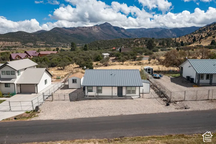 White exterior with a grey metal roof and a gravel lot