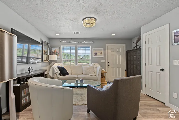 Recessed lighting, wood-finish flooring, two panel doors, multiple windows with blinds, and a built-in media console