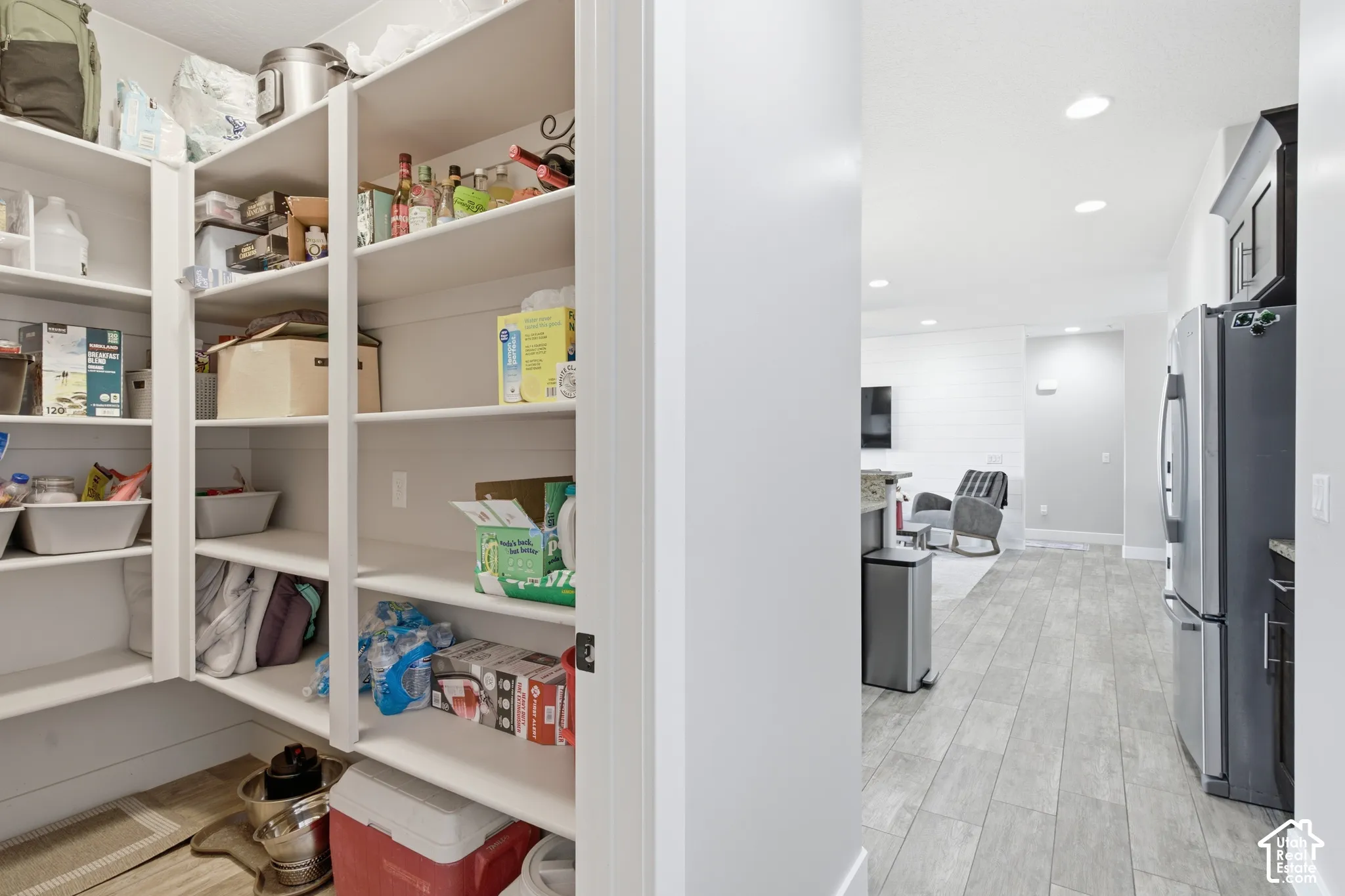 Walk-in pantry with ample shelving, recessed lighting, wood-finish flooring, and stainless steel appliances