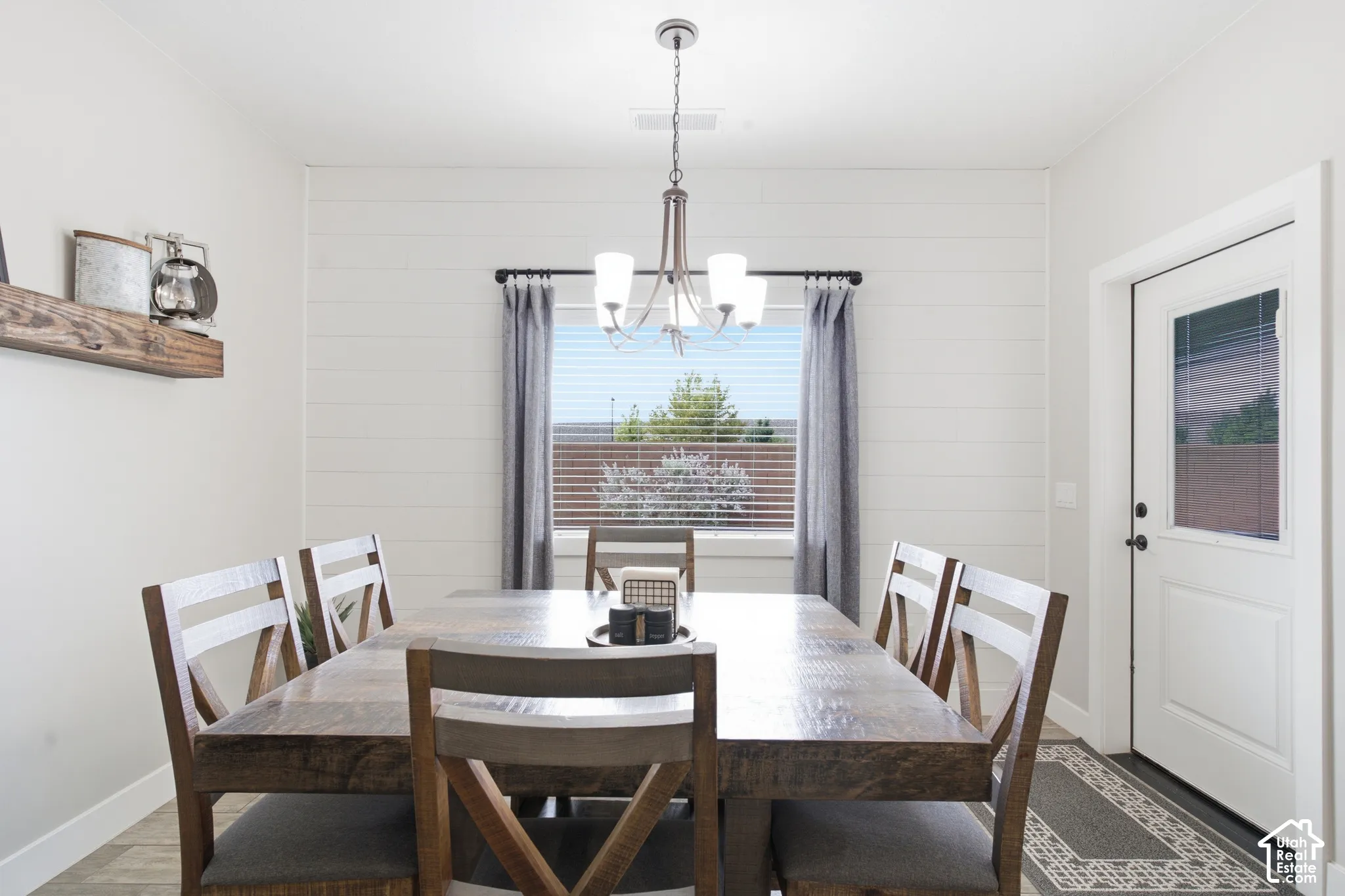 White shiplap accent wall, wood-finish flooring, and a contemporary chandelier