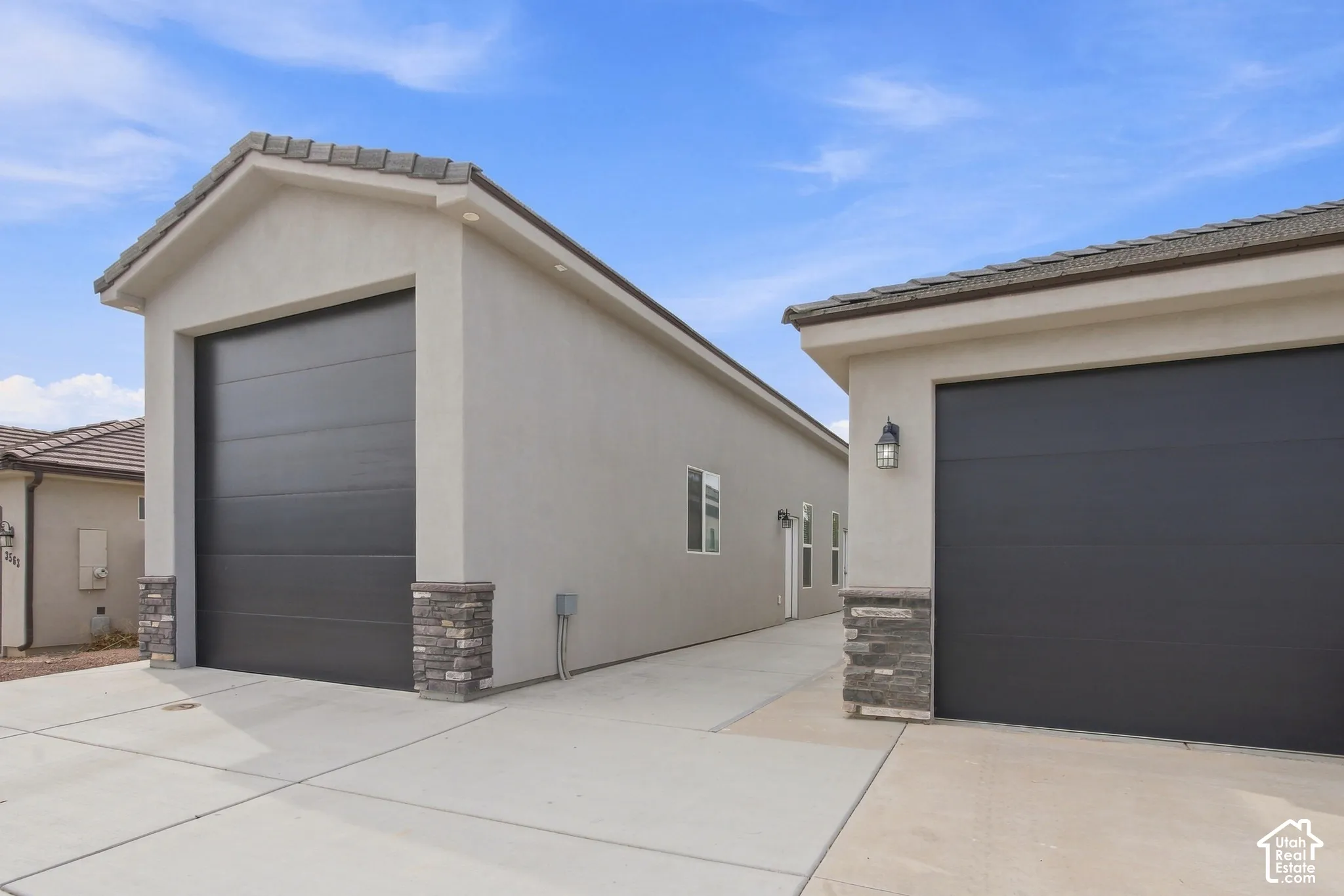 Attached single-car garage featuring a dark panel door, stucco exterior, and stone veneer accents