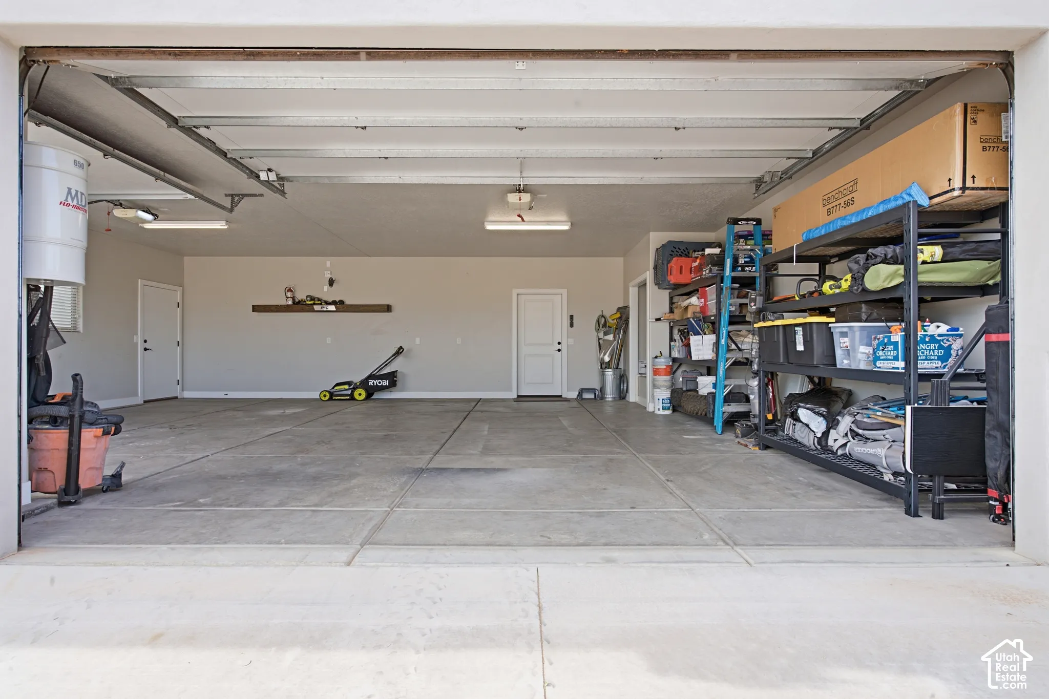 Concrete flooring with overhead lighting, a floating wall shelf, and two interior doors