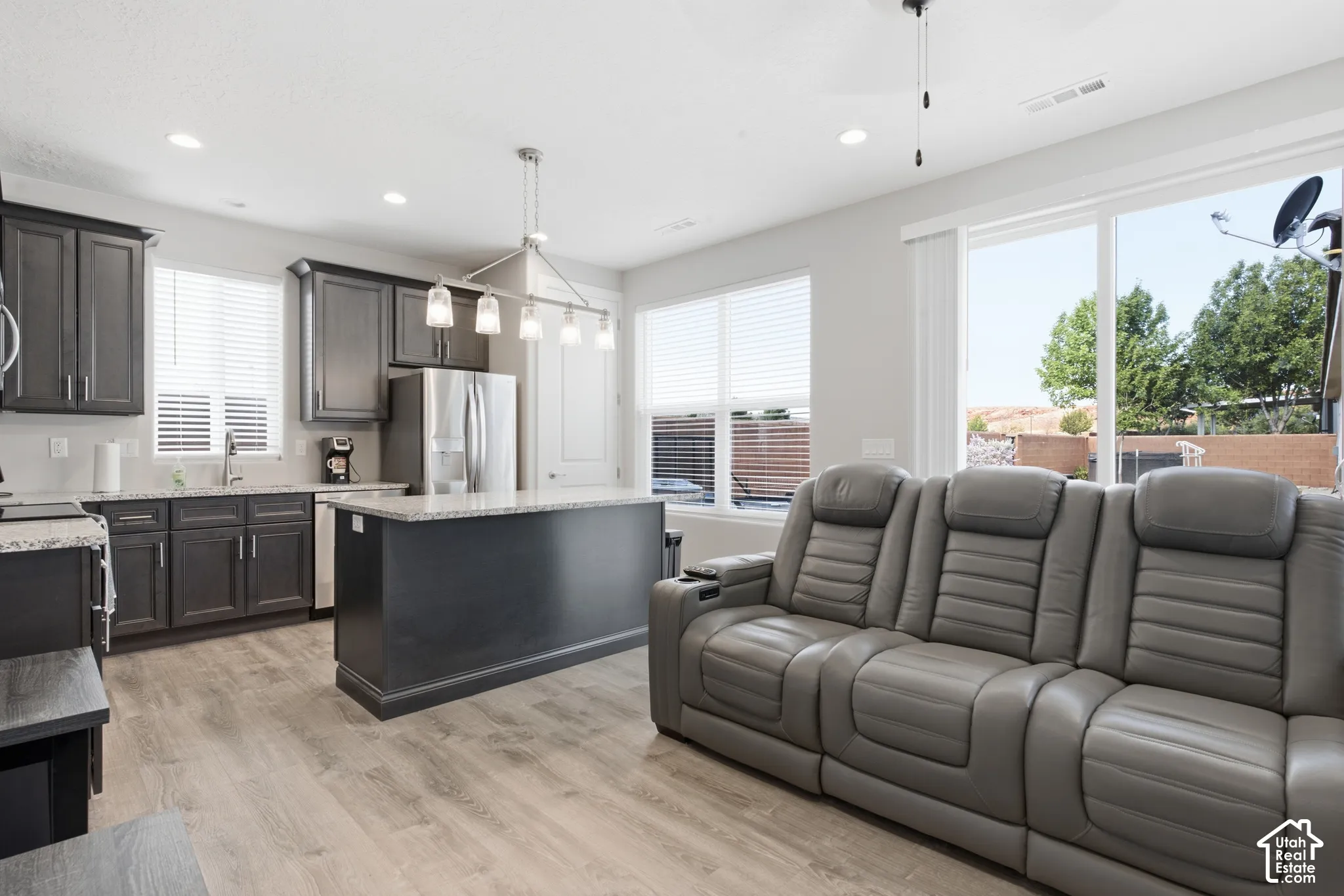 Open-concept living area with wood-finish flooring, recessed lighting, and sliding glass door