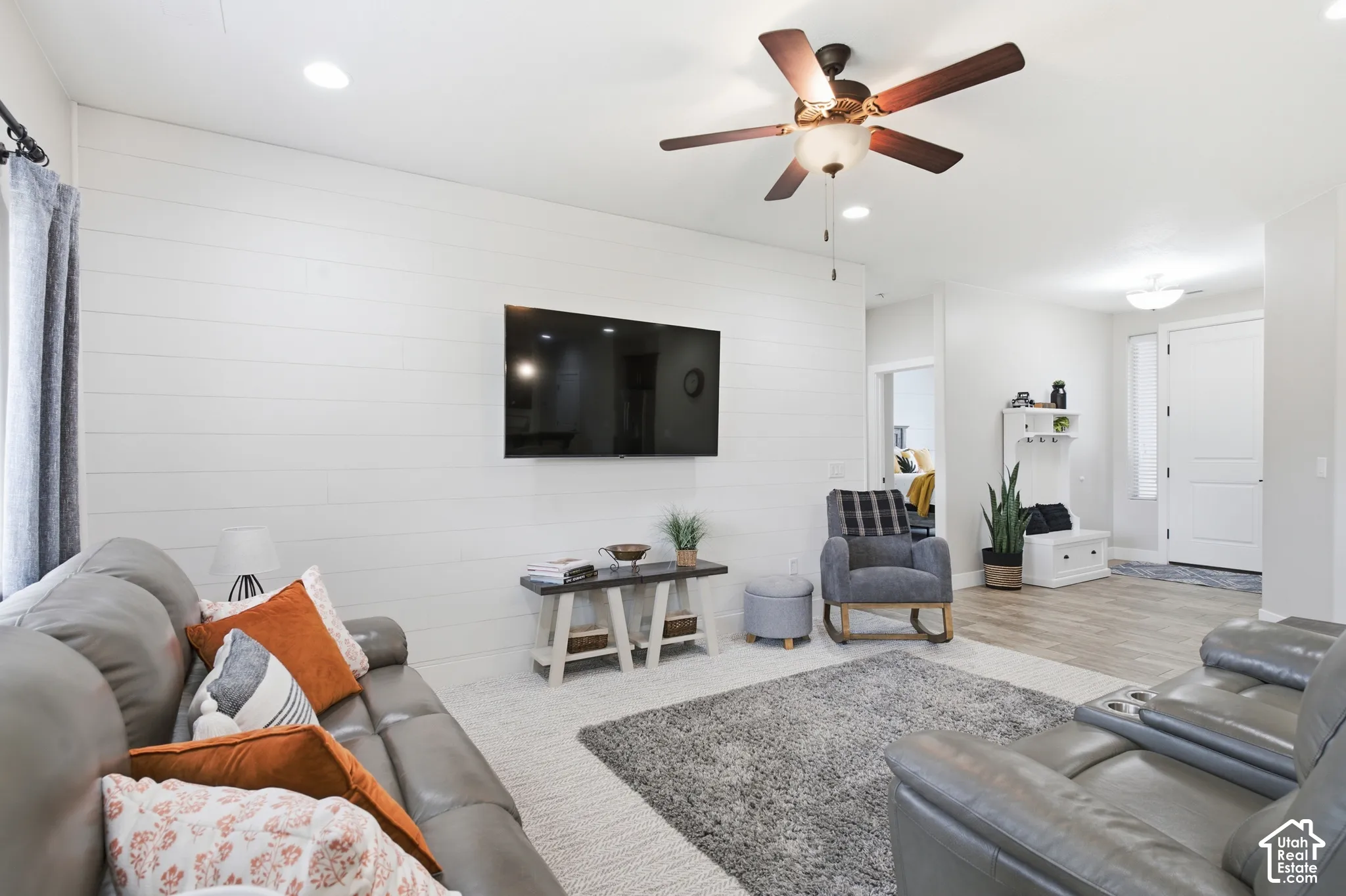 Recessed lighting, ceiling fan with light fixture, shiplap accent wall, wood-finish flooring, and white paneled entry door