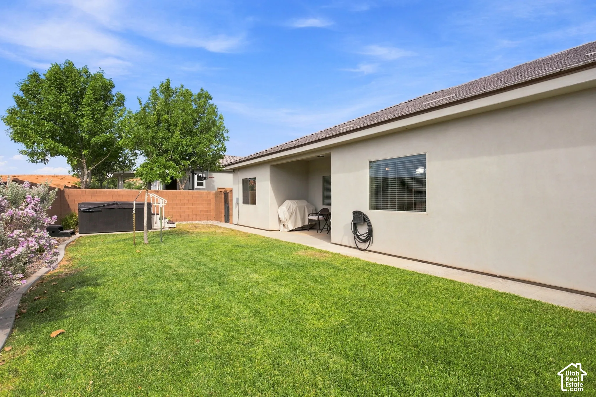 Expansive lawn area with a concrete patio and a hot tub