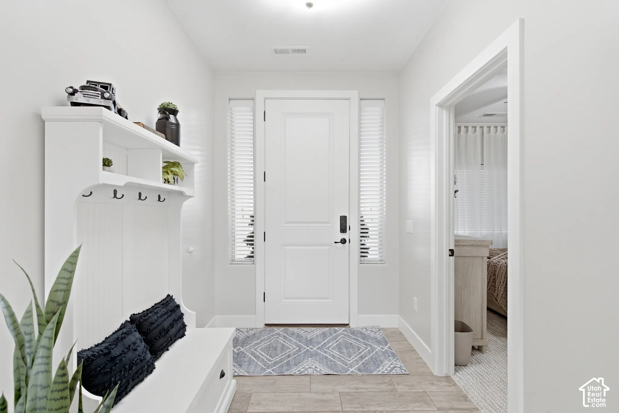 Entryway featuring a built-in hall tree with storage bench, tiled flooring, and a solid-core entry door with sidelight windows