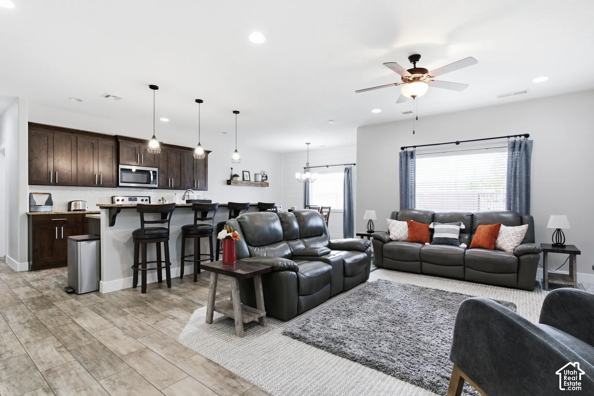 Wood-finish flooring throughout, dark wood-finish cabinetry, stainless steel microwave, recessed lighting, and a ceiling fan with integrated lighting