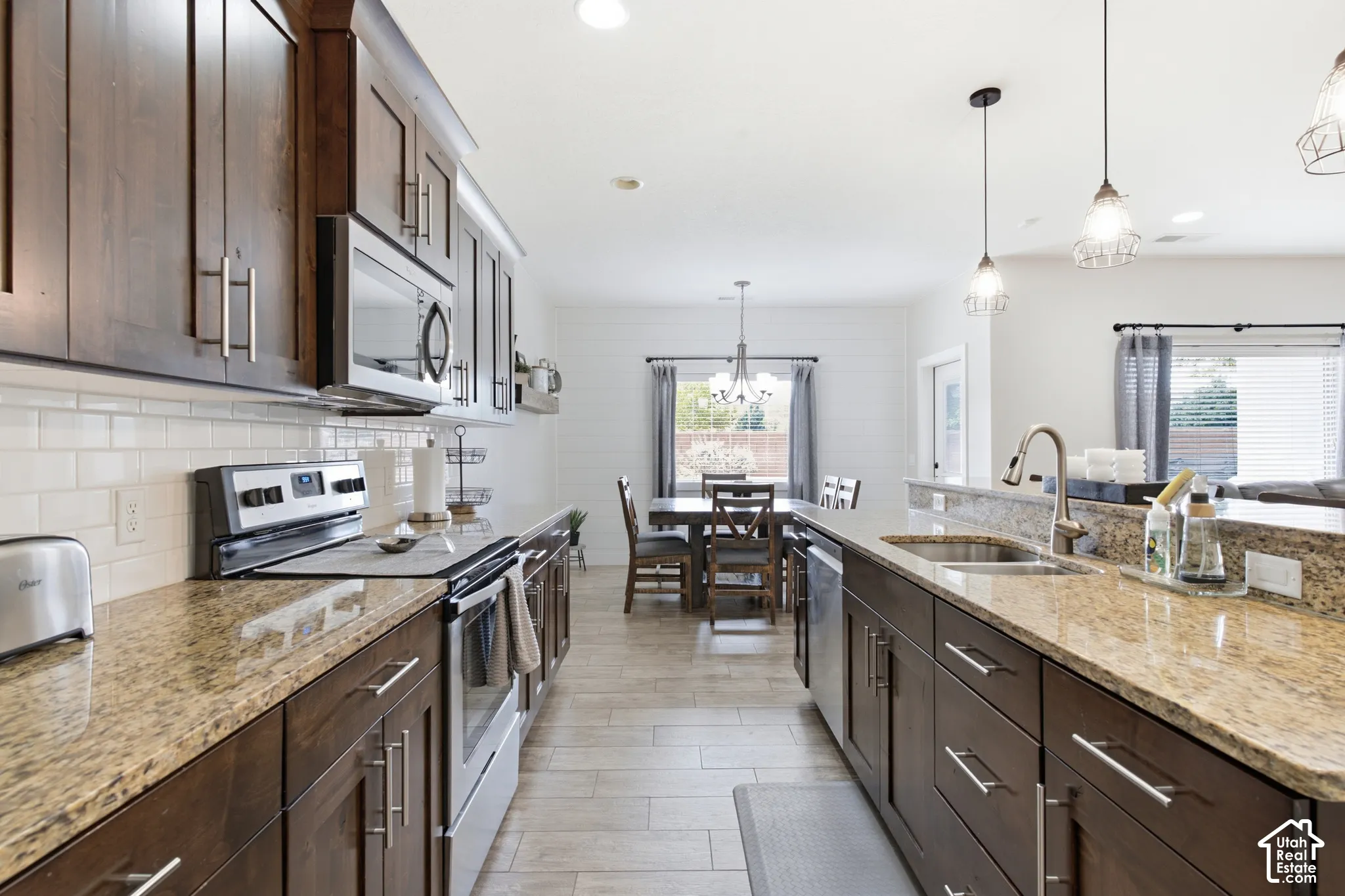 Kitchen featuring wood cabinetry, stainless steel appliances, speckled stone countertops, and a subway tile backsplash