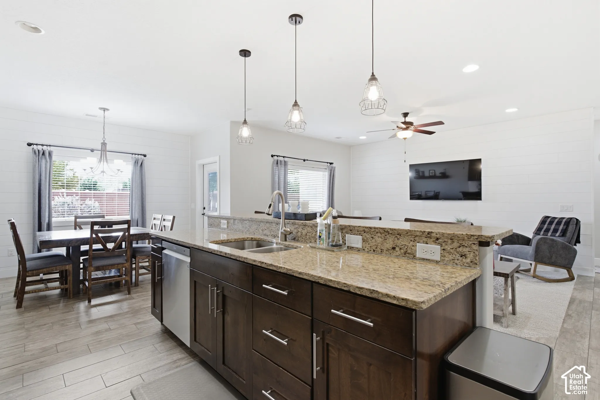 Kitchen island with stone countertops, dark wood cabinetry, and stainless steel sink