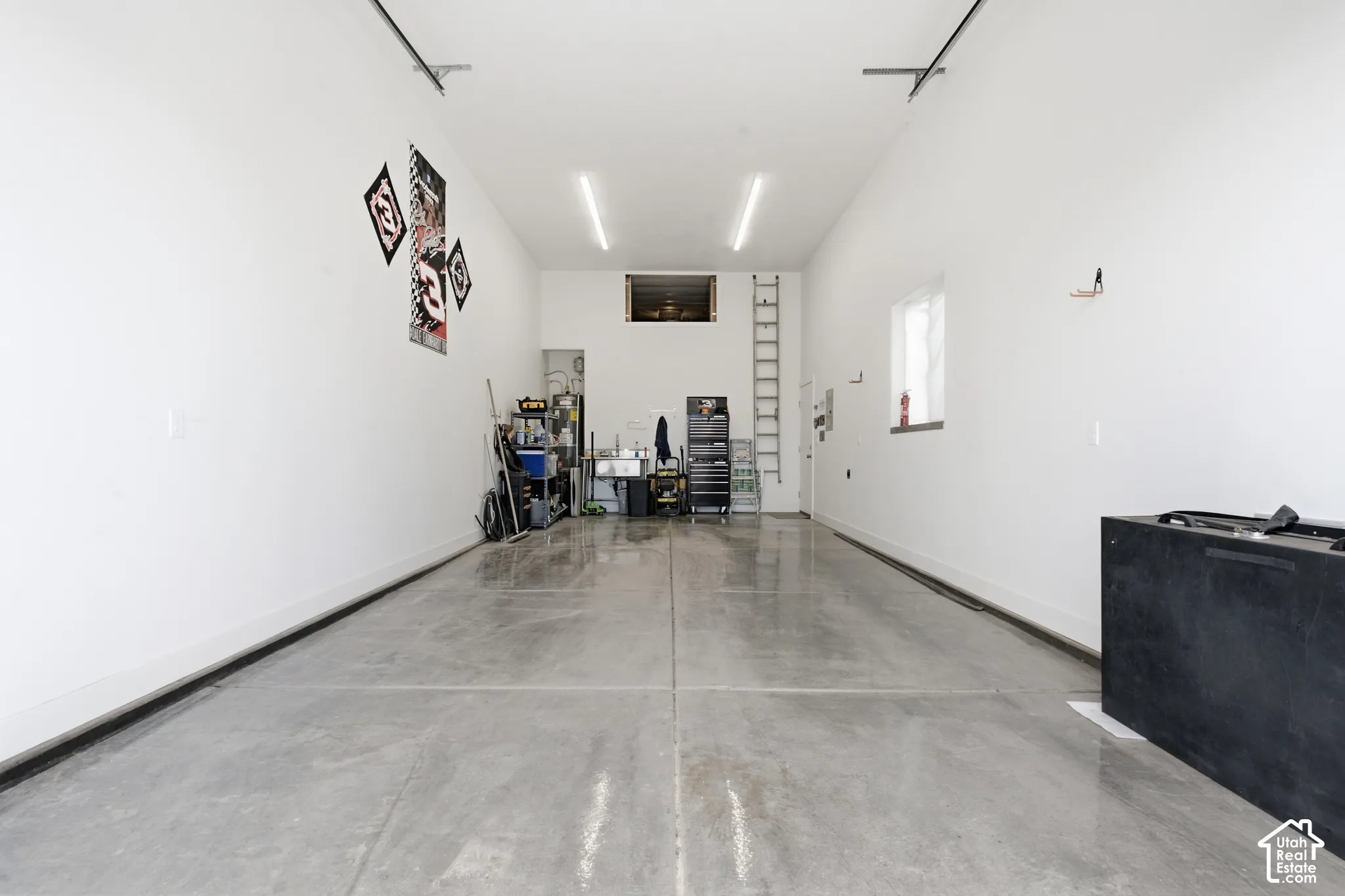 Expansive garage with polished concrete flooring, white painted walls, and overhead strip lighting