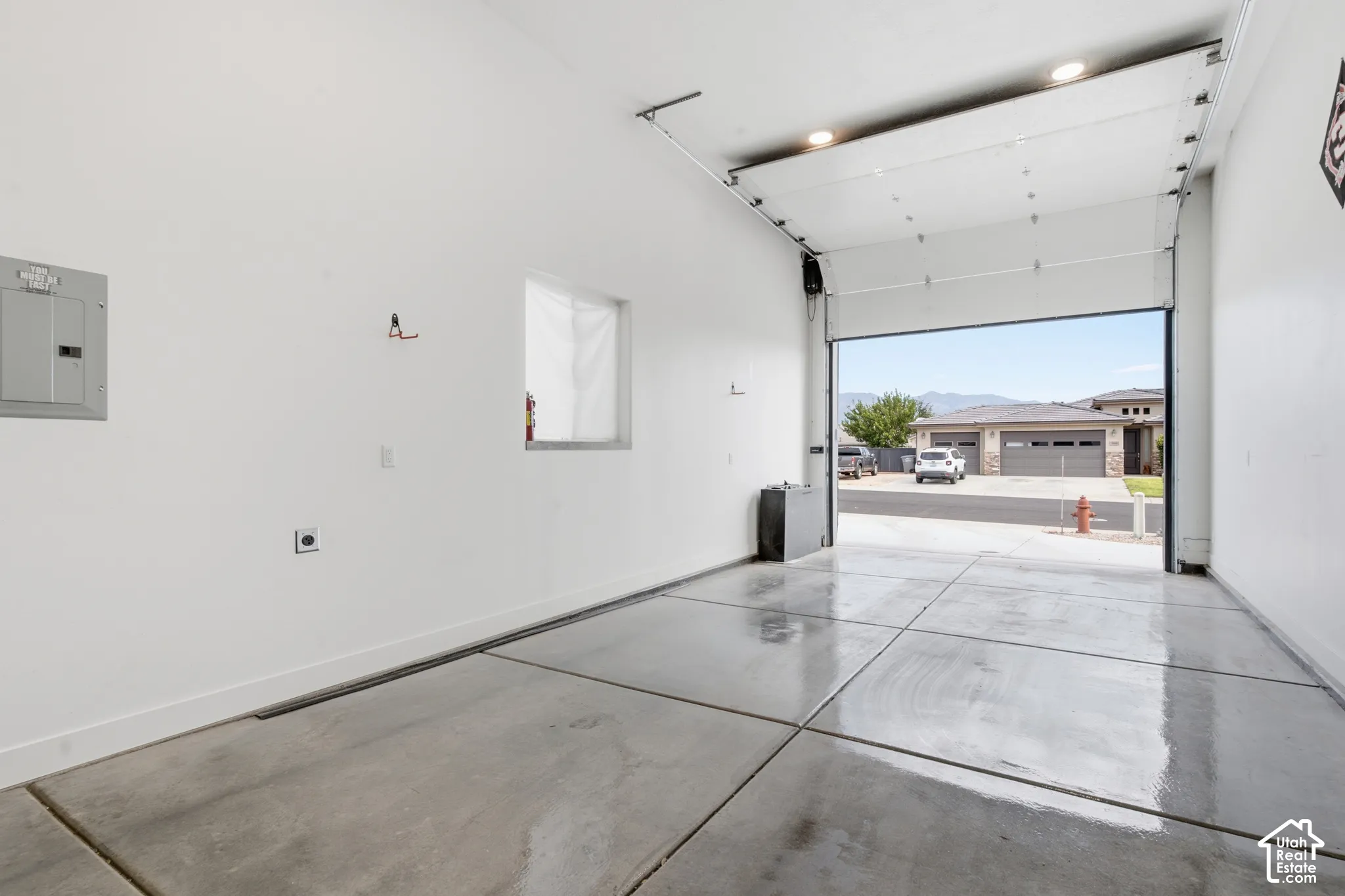 Attached garage with a roll-up door, recessed lighting, concrete flooring, and a wall-mounted electrical panel