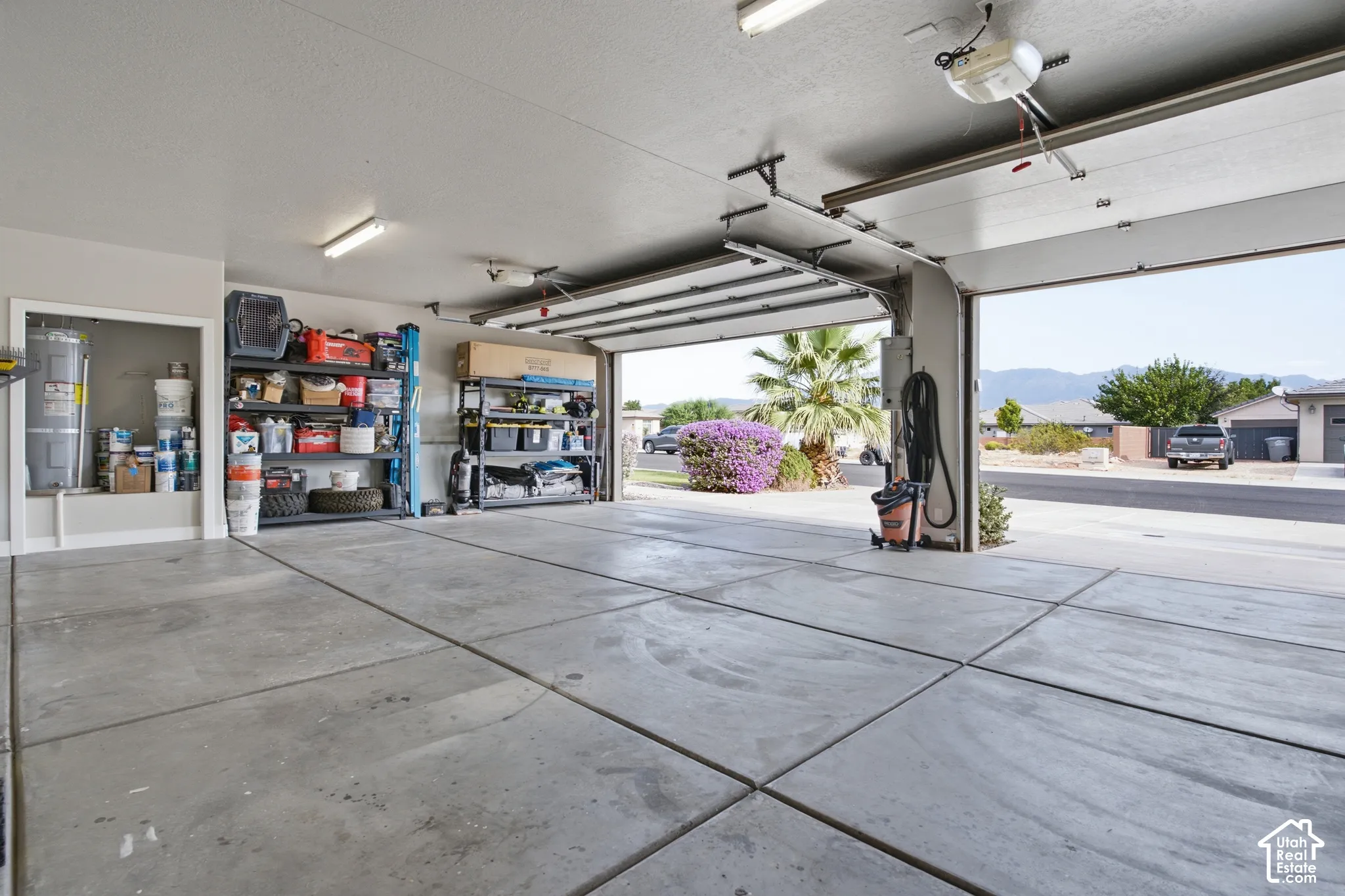 Attached two-car garage with concrete flooring, fluorescent lighting, and an overhead garage door opener