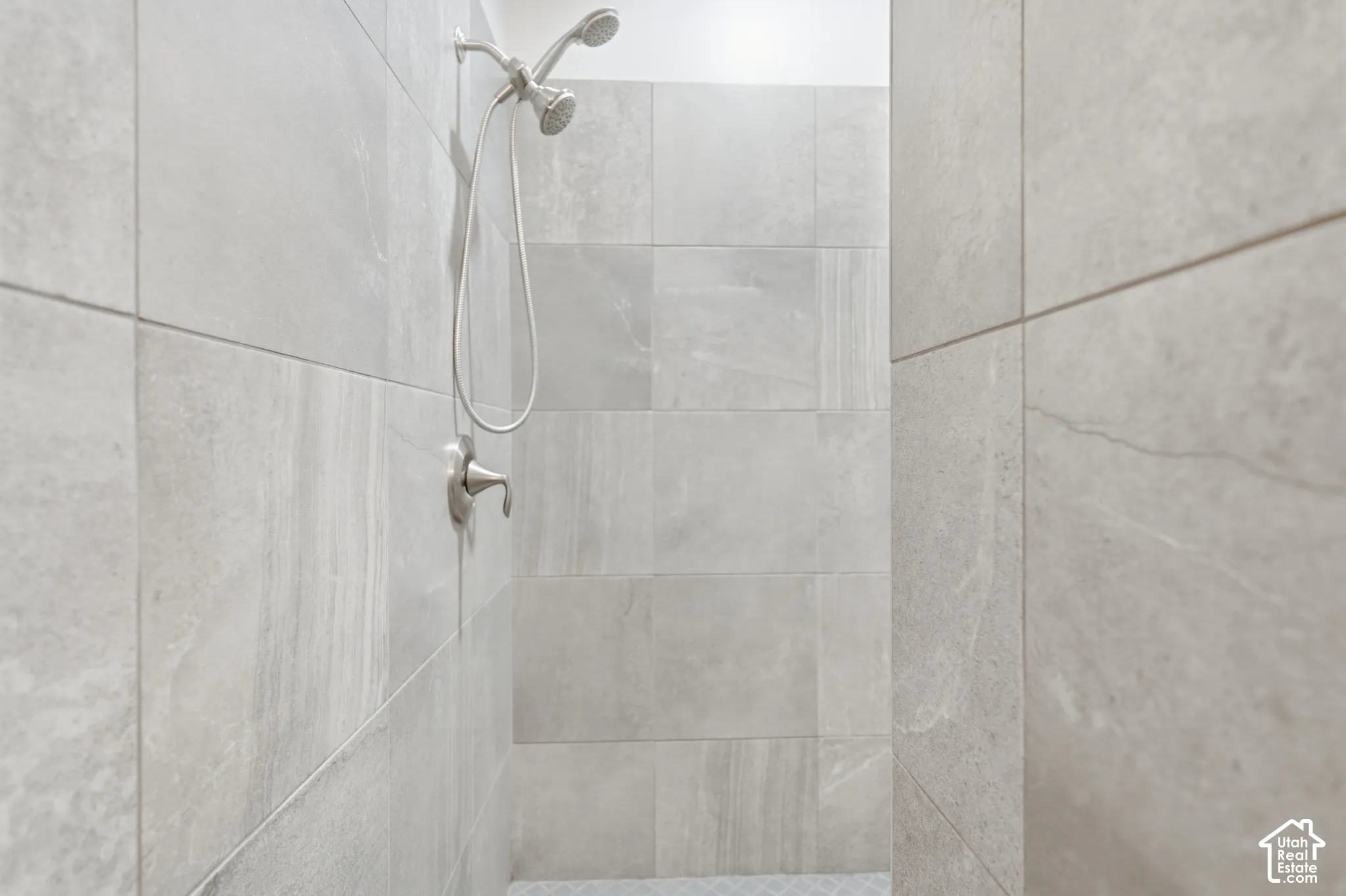 Shower enclosure featuring large format stone-look wall tiles and a brushed nickel shower fixture