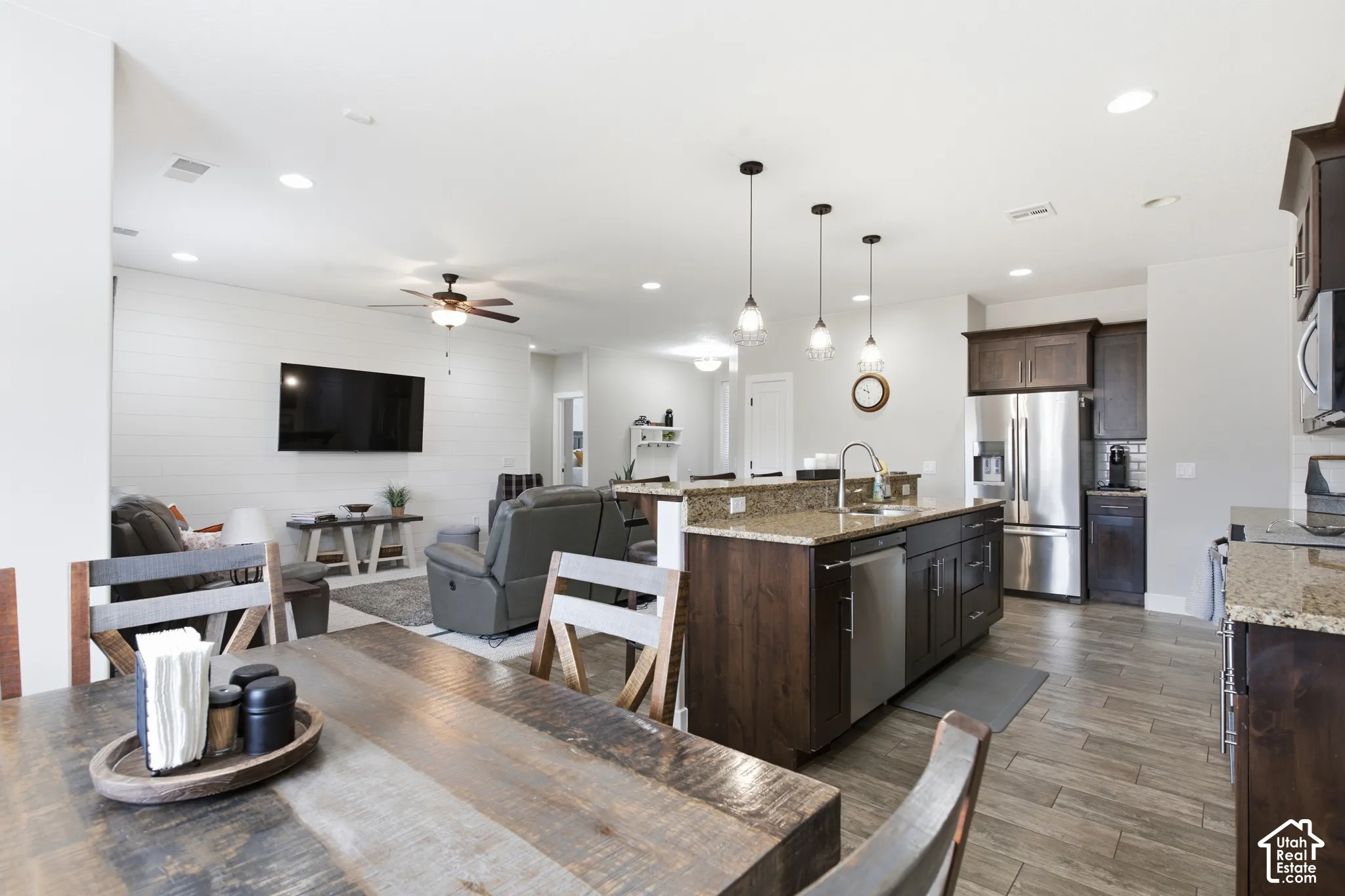Open concept layout, recessed lighting, wood-finish flooring, kitchen island with built-in sink, stainless steel appliances