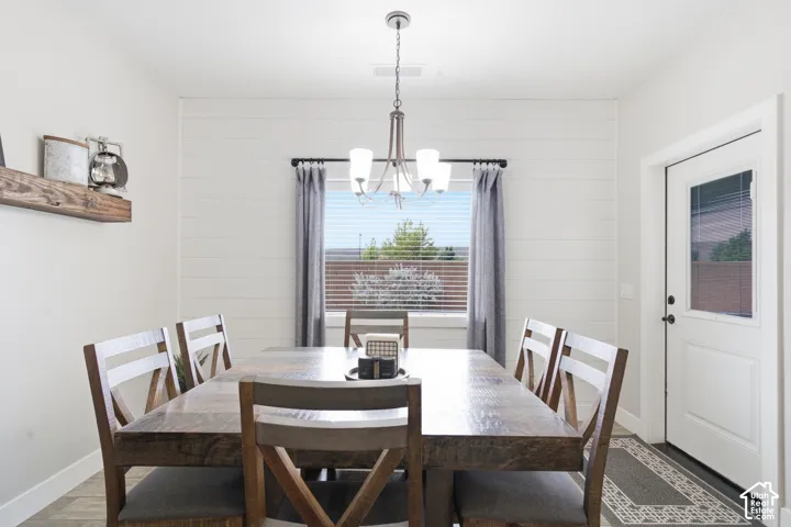 White shiplap accent wall, wood-finish flooring, and a contemporary chandelier