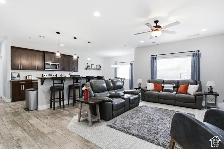 Wood-finish flooring throughout, dark wood-finish cabinetry, stainless steel microwave, recessed lighting, and a ceiling fan with integrated lighting