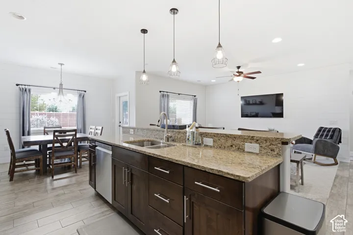 Kitchen island with stone countertops, dark wood cabinetry, and stainless steel sink