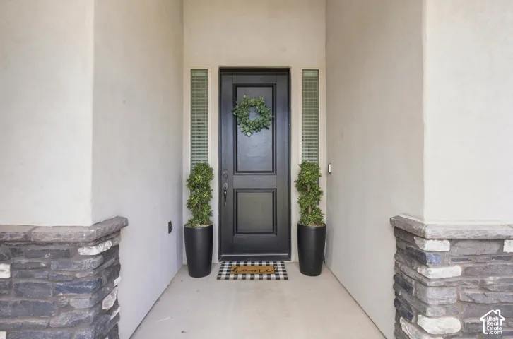 Entryway featuring a black panel door, vertical frosted sidelights, stucco walls, and stone veneer accents