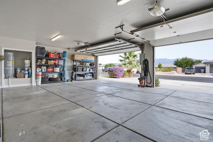 Attached two-car garage with concrete flooring, fluorescent lighting, and an overhead garage door opener
