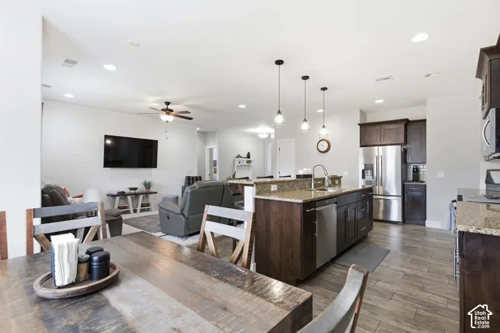 Open concept layout, recessed lighting, wood-finish flooring, kitchen island with built-in sink, stainless steel appliances